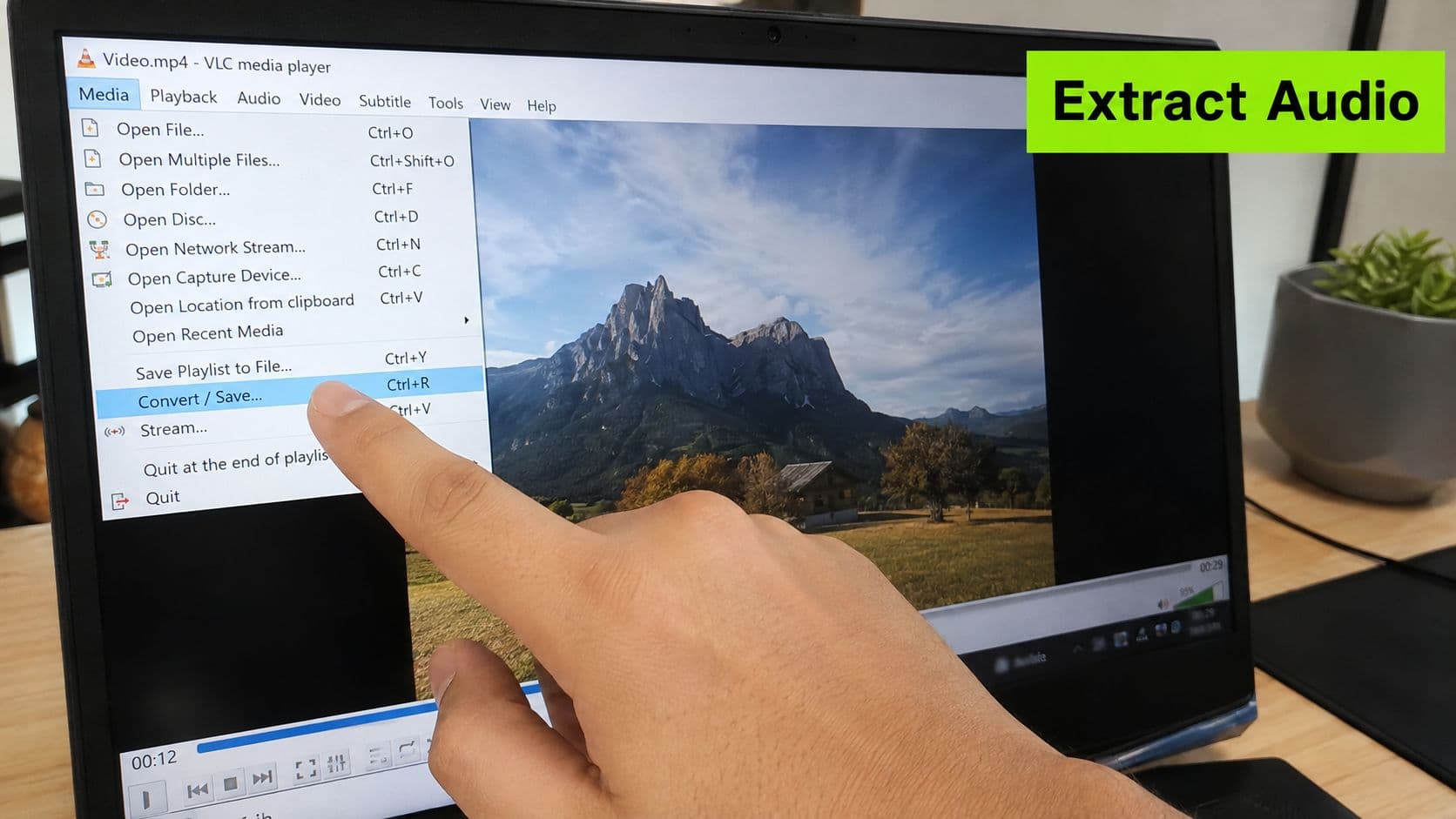 A person selecting the Convert / Save option in the VLC media player interface on a laptop.