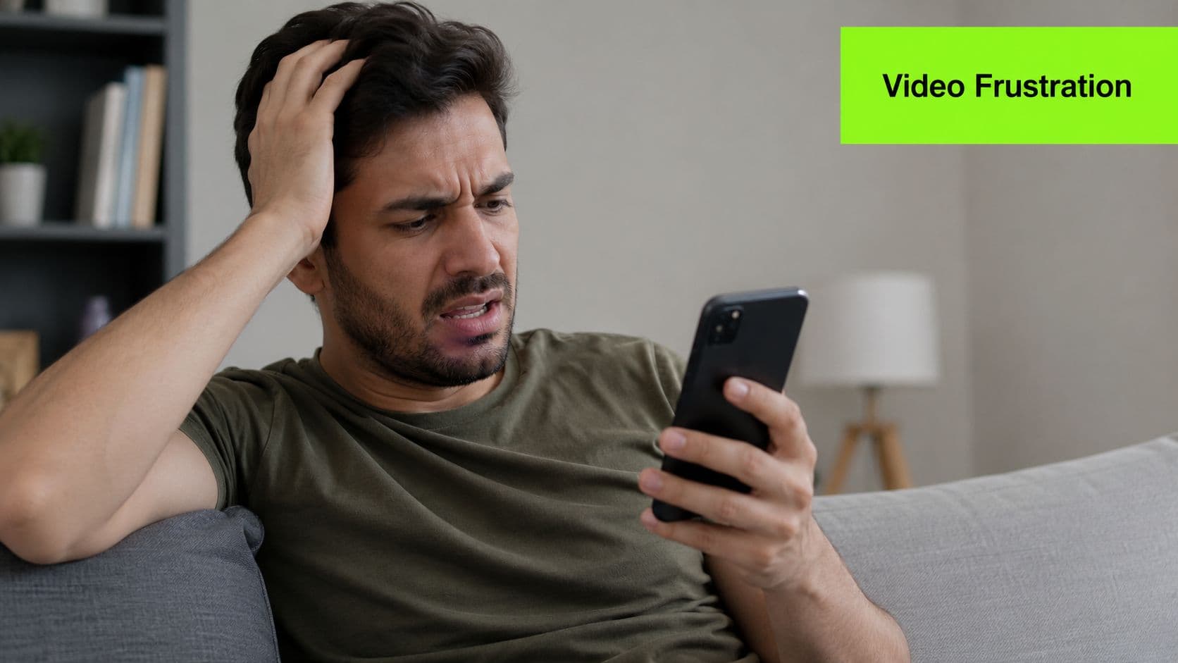 A frustrated man looking at his smartphone while sitting on a sofa in his living room.