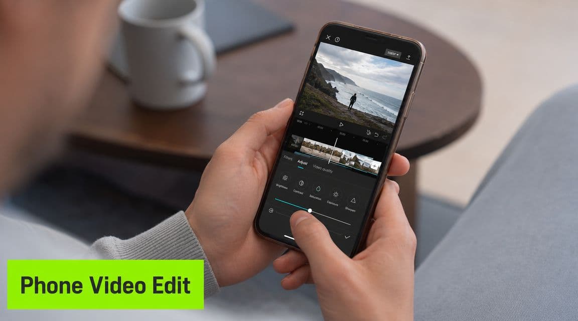 A person editing a travel video on their smartphone screen while sitting at a wooden table.